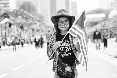 Portrait of girl holding flag while standing on street