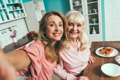 Daughter doing selfie with mother at kitchen