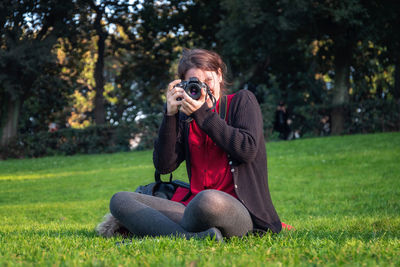 Young woman photographing camera on grass