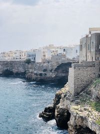 Buildings by sea against sky