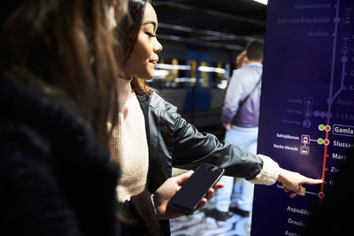 Female friends reading illuminated map at subway station