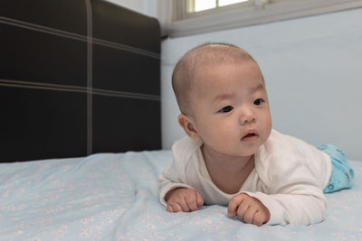 Portrait of cute baby lying on bed