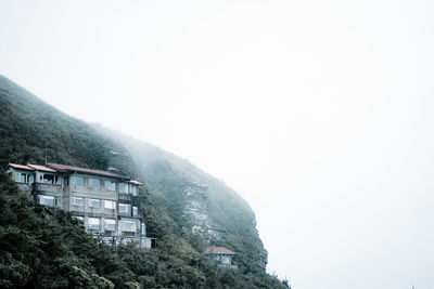 Buildings by mountain against sky