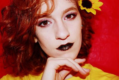 Close-up portrait of beautiful young woman with make-up against red background