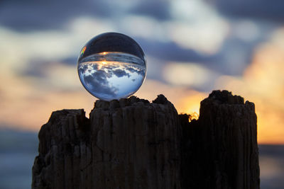 Close-up of rock on wooden post against sky