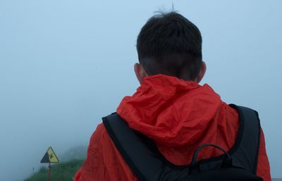 Rear view of man with backpack standing during foggy weather