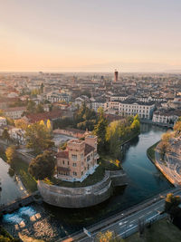 High angle view of buildings by river against sky during sunset