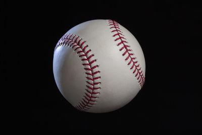 Close-up of baseball against black background