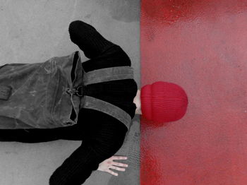 Low section of man standing on red umbrella