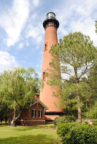 Low angle view of lighthouse by building against sky