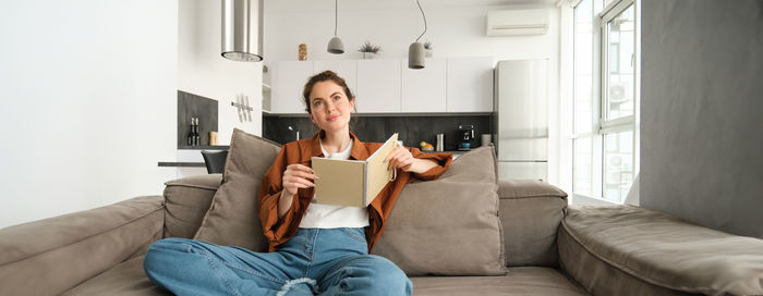 Young woman using mobile phone while sitting on sofa at home