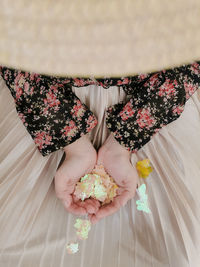 Two hands of a girl carrying tiny colorful leaf decoration on her skirt