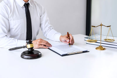 Midsection of judge writing in book at table