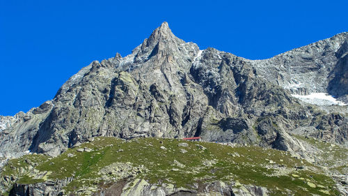 Low angle view of snowcapped mountains against clear blue sky