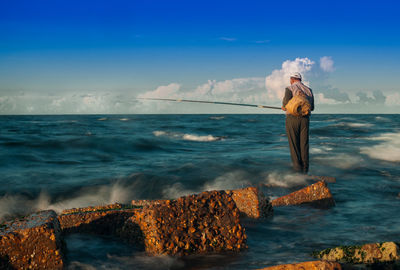 Man standing at beach against sky