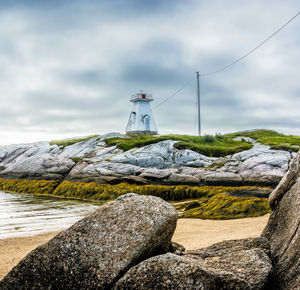Terence bay lighthouse by rocks against sky