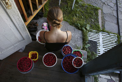 High angle view of woman with fruits in containers sitting at doorway