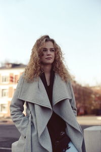 Portrait of beautiful young woman standing against sky