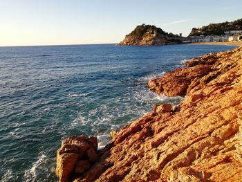 Scenic view of rocks in sea against clear sky