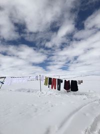 Clothes drying on snow covered field against sky