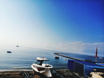 Boats moored in sea against blue sky