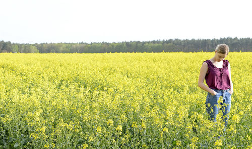 Woman standing amidst oilseed rape