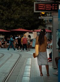 Rear view of people walking on railway bridge in city