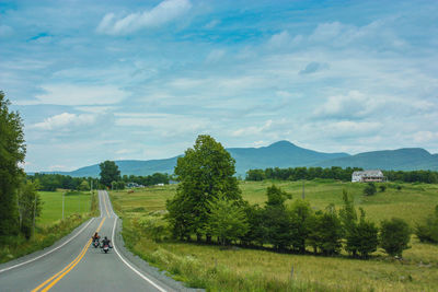 Road amidst green landscape against sky