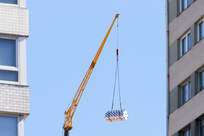 Industrial crane telescopic vehicle working between two buildings in construction site with blue sky