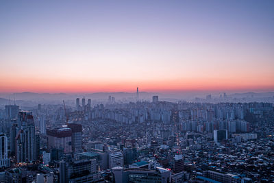 Aerial view of buildings in city against sky during sunset