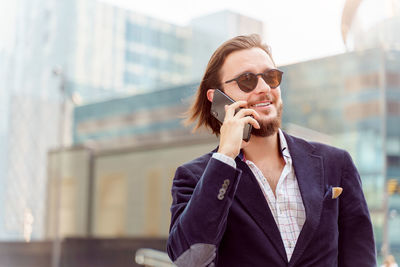 Smiling businessman talking on phone outdoors