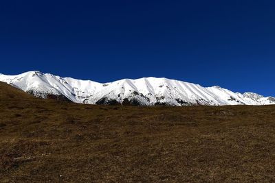 Scenic view of snowcapped mountains against clear blue sky