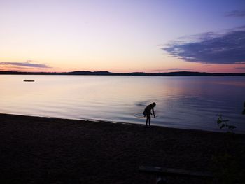 Silhouette man standing on beach against sky during sunset