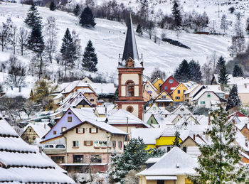 Low angle view of church amidst houses against snowcapped mountain