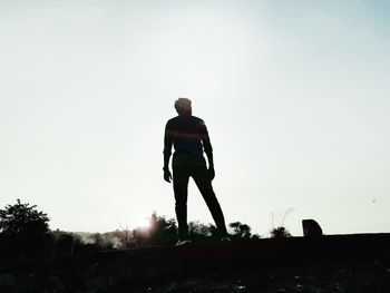 Rear view of man standing on field against clear sky