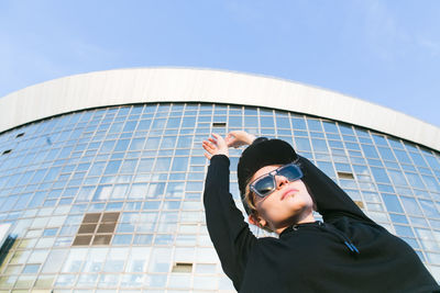 Low angle view of young woman standing against building