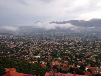 Aerial view of city against cloudy sky