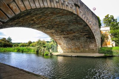 Arch bridge over river against sky