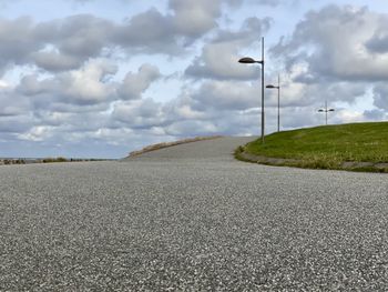 Road amidst field against sky