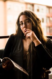 Portrait of young woman reading magazine at home