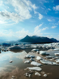 Scenic view of calm lagoon with ice bergs against sky