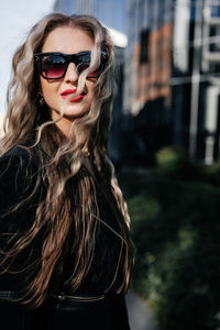 Portrait of young woman wearing sunglasses against trees