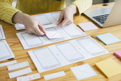 Midsection of woman holding paper on table