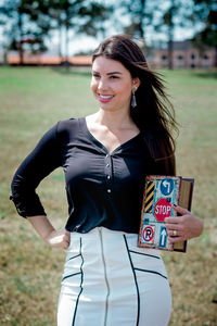 Portrait of smiling young woman standing on field