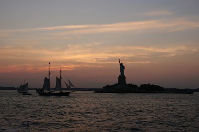 Silhouette boats in calm sea against the sky