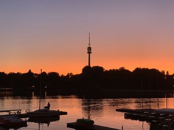 Silhouette of communications tower in canal during sunset