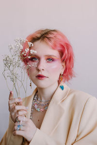 Portrait of young woman with flowers against white background