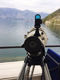 Close-up of coin-operated binoculars against river