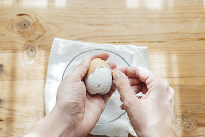 Cropped hand of person holding seashell on table