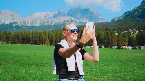 Full length of woman drinking water while standing on field